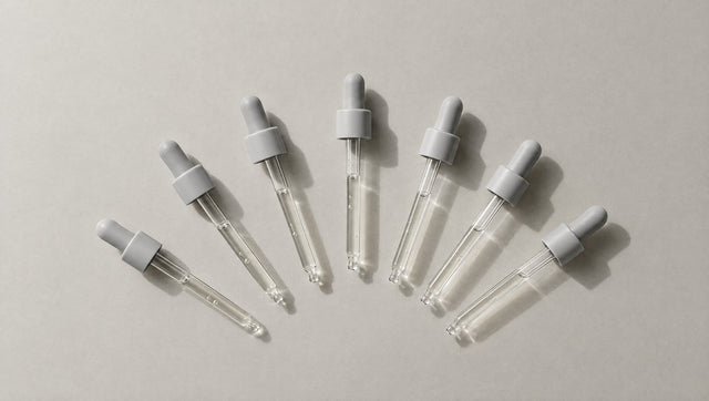 Eight identical glass droppers laid out in a fan