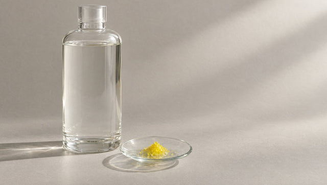 Large bottle of clear toner beside a dish of yellow crystals